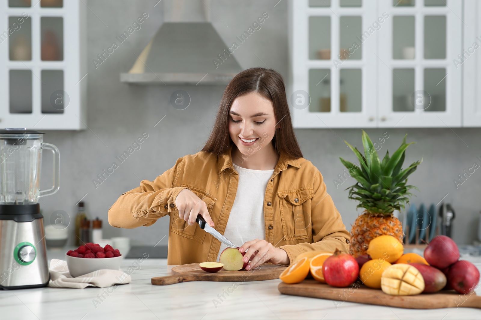 Photo of Woman preparing ingredients for tasty smoothie at white marble table in kitchen