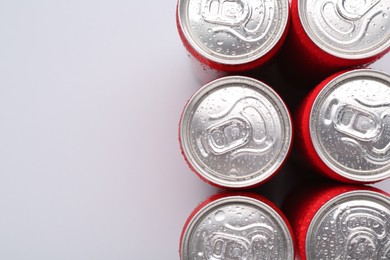 Photo of Energy drinks in wet cans on light grey background, top view. Space for text