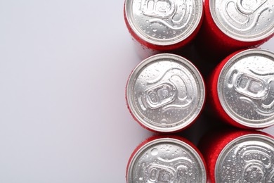 Energy drinks in wet cans on light grey background, top view. Space for text