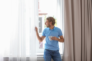 Photo of Young man having rest near window with open curtains at home