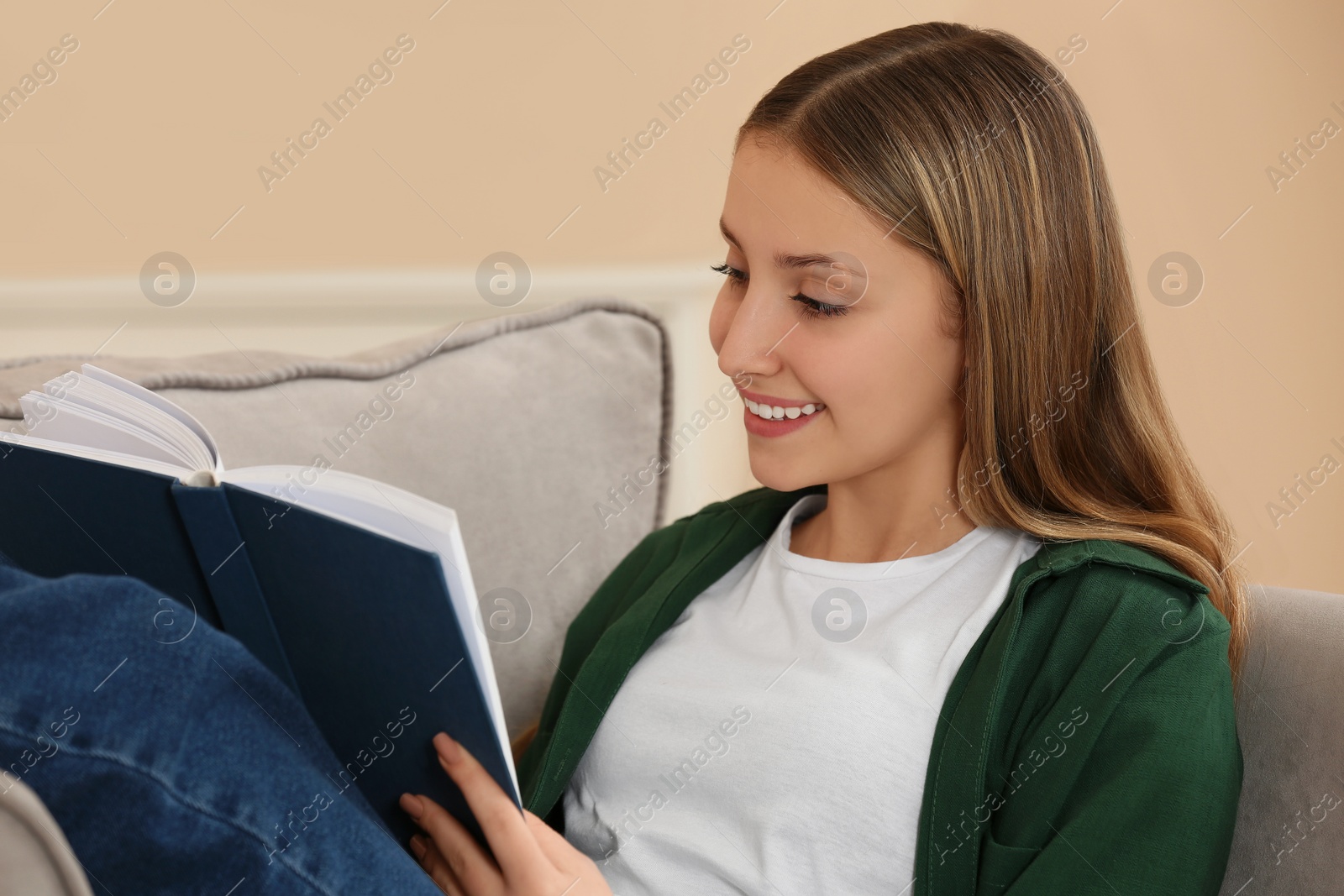 Photo of Teenage girl reading book in armchair at home