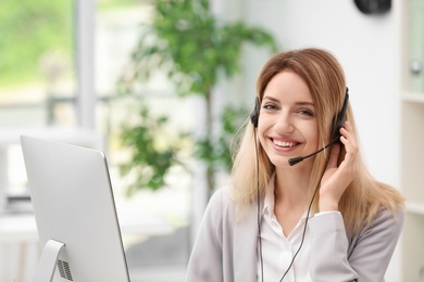 Photo of Young female receptionist with headset in office