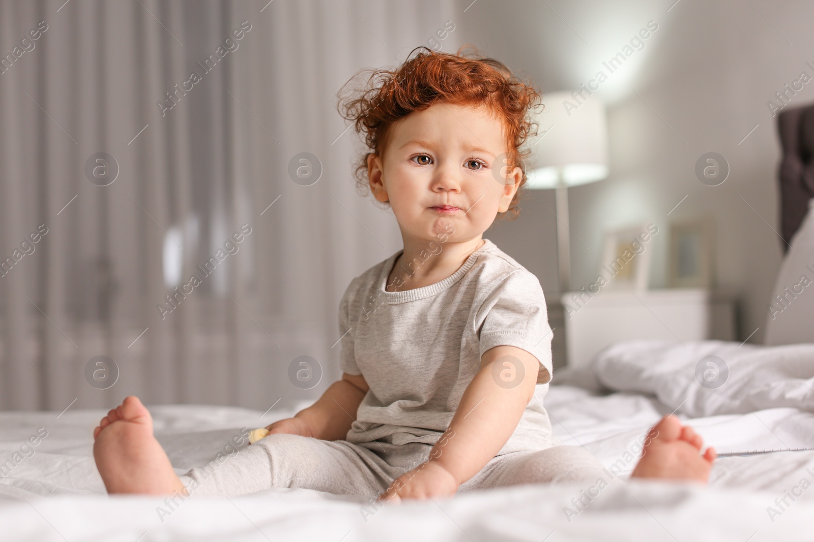 Photo of Cute little child sitting on bed at home