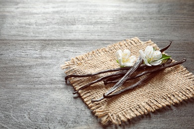 Photo of Vanilla sticks and flowers on wooden background