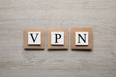 Photo of Paper notes with acronym VPN on wooden table, flat lay