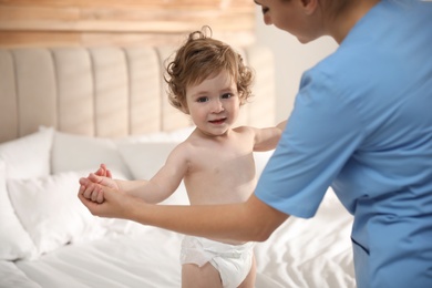 Orthopedist examining cute little baby on bed