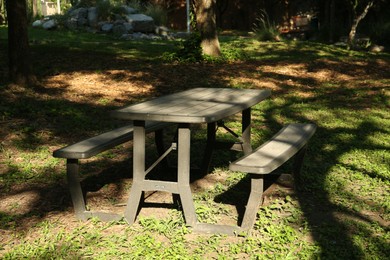 Photo of Empty wooden picnic table with benches in park on sunny day