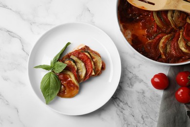 Delicious ratatouille served with basil on white marble table, flat lay