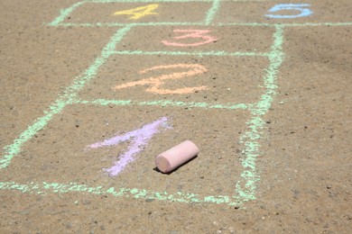 Photo of Hopscotch drawn with colorful chalk on asphalt outdoors, closeup