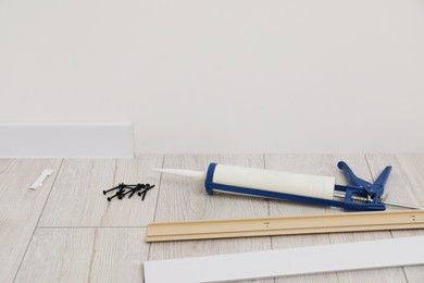 Plinths, caulking gun and screws on laminated floor in room