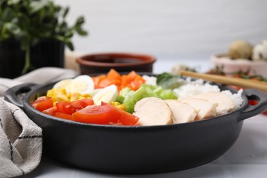 Delicious poke bowl with meat, egg, rice and vegetables on table, closeup