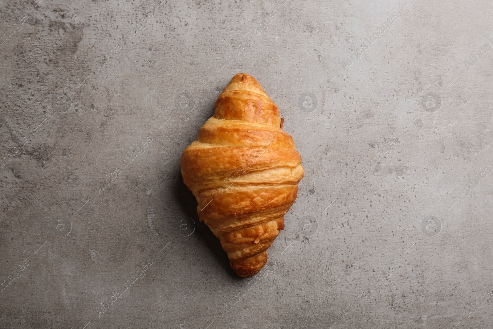 Photo of Tasty croissant on grey background, top view. French pastry