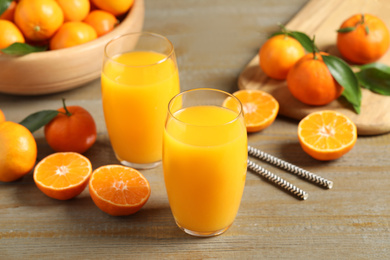 Photo of Glasses of fresh tangerine juice and fruits on wooden table