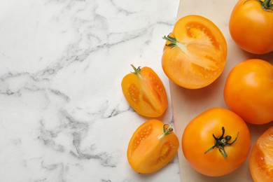 Photo of Fresh ripe yellow tomatoes on white marble table, flat lay. Space for text