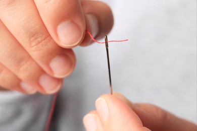 Photo of Closeup view of woman threading sewing needle