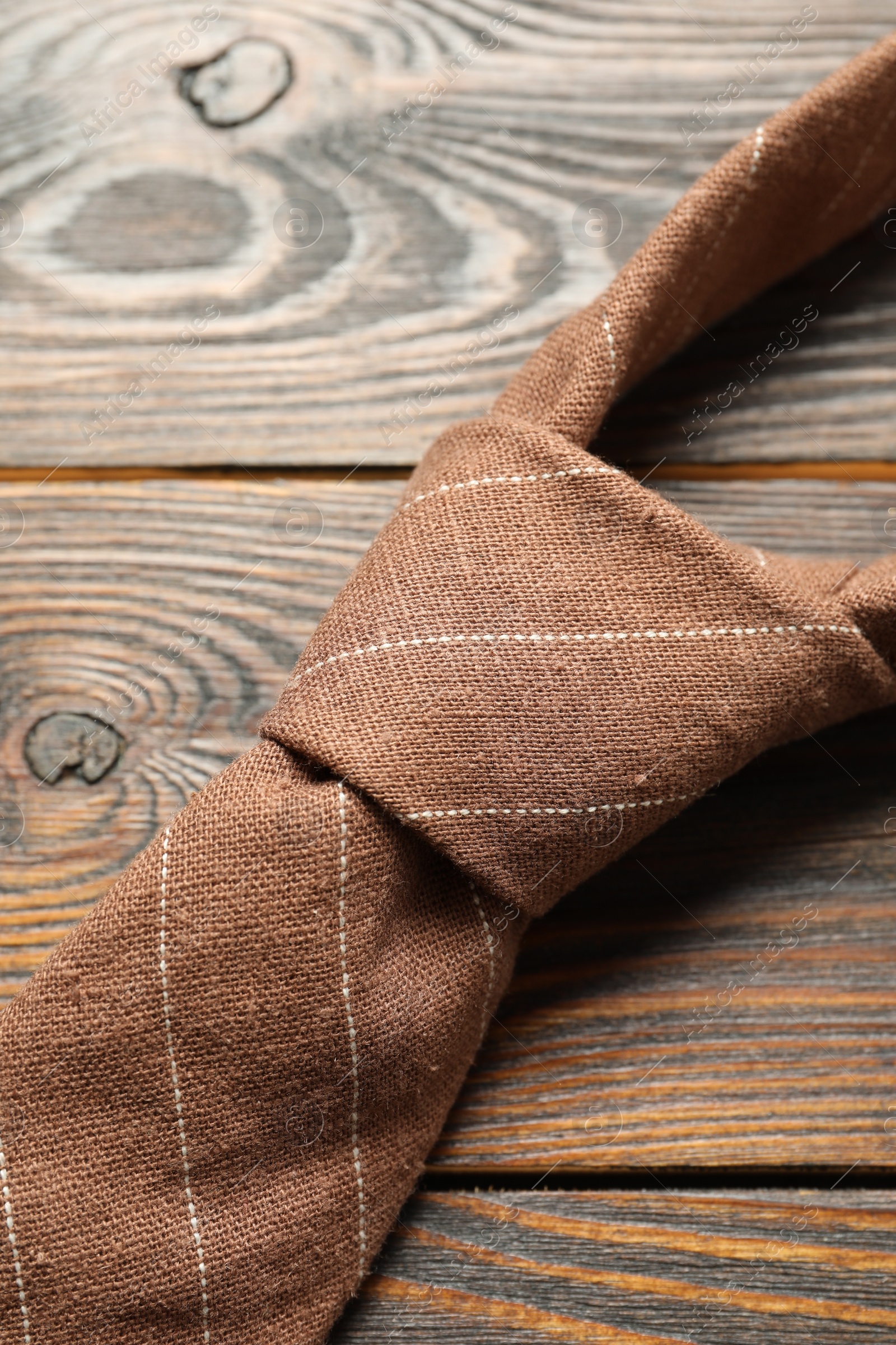 Photo of One striped necktie on wooden table, top view