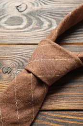 Photo of One striped necktie on wooden table, top view
