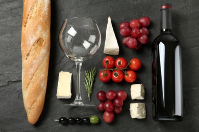 Flat lay composition with red wine and snacks on black table