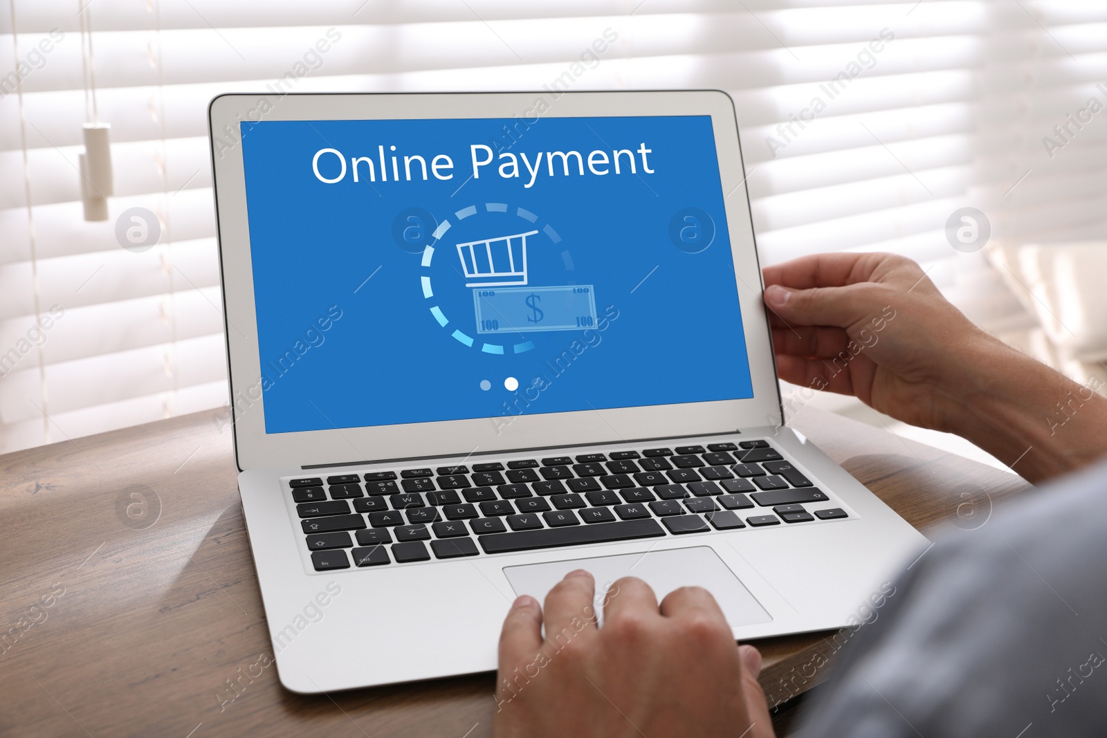 Image of Man using laptop for online payment at wooden table, closeup