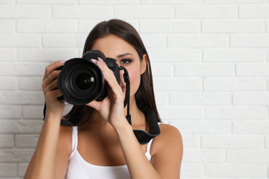 Photo of Professional photographer working near white brick wall in studio. Space for text