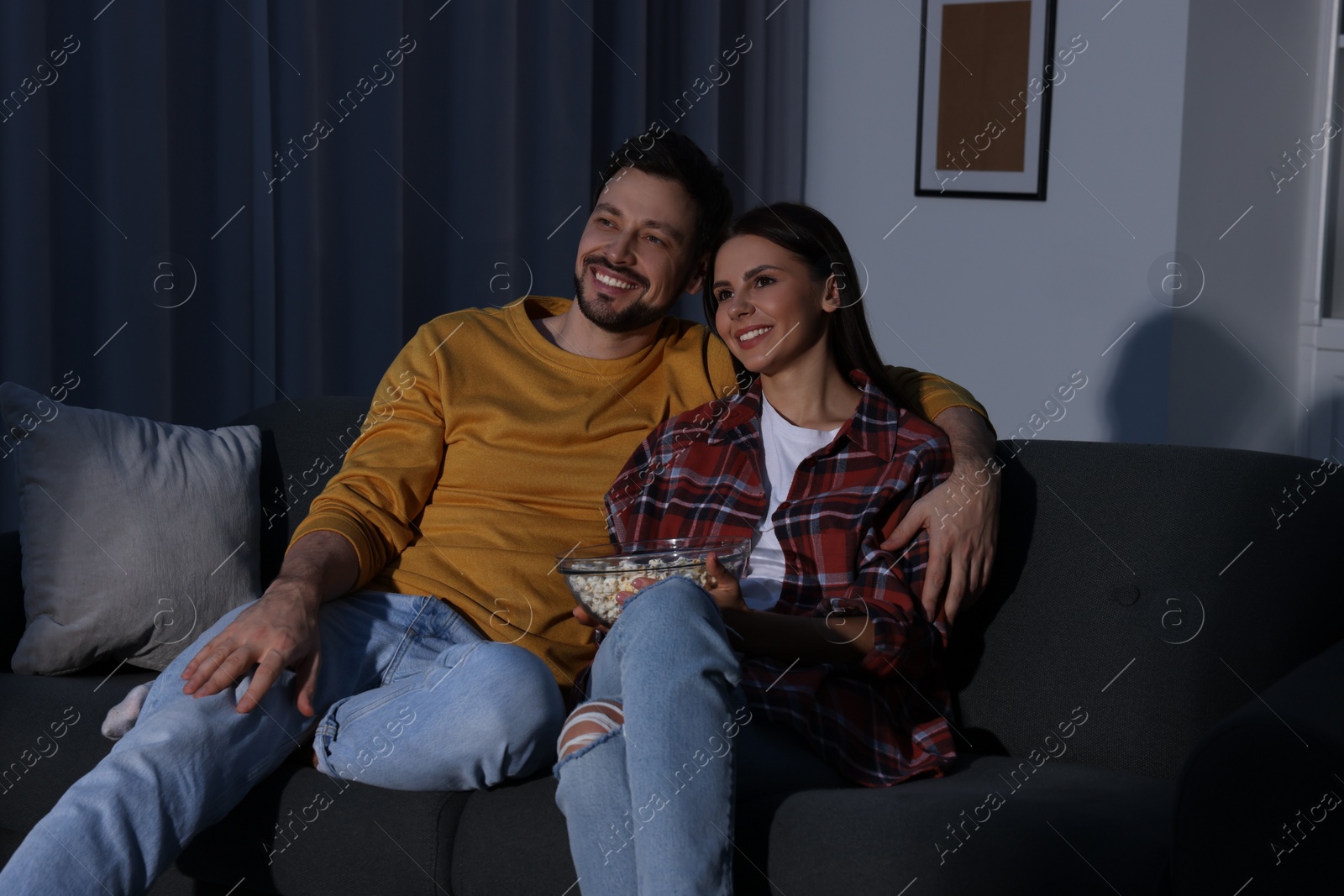 Photo of Happy couple watching TV at home in evening