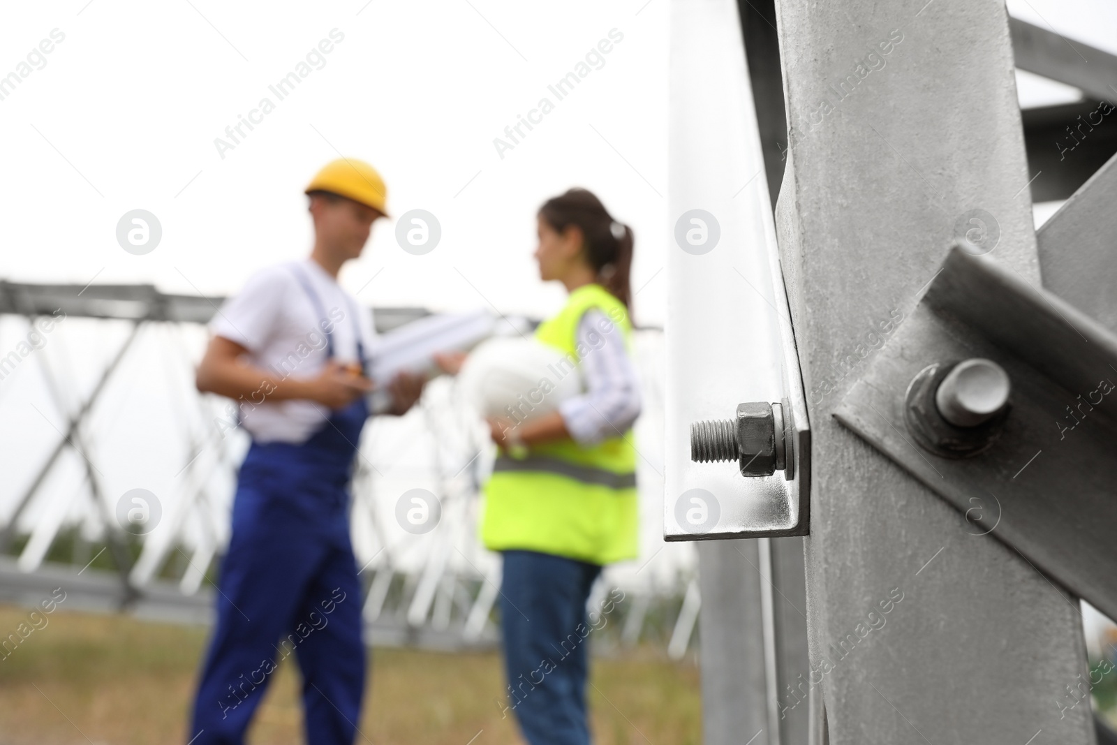 Photo of High voltage tower construction and blurred engineers on background. Installation of electrical substation