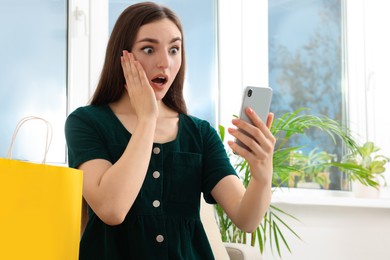 Special Promotion. Emotional woman looking at smartphone near window indoors