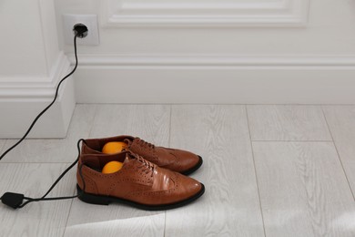 Photo of Shoes with electric dryer on floor indoors, space for text