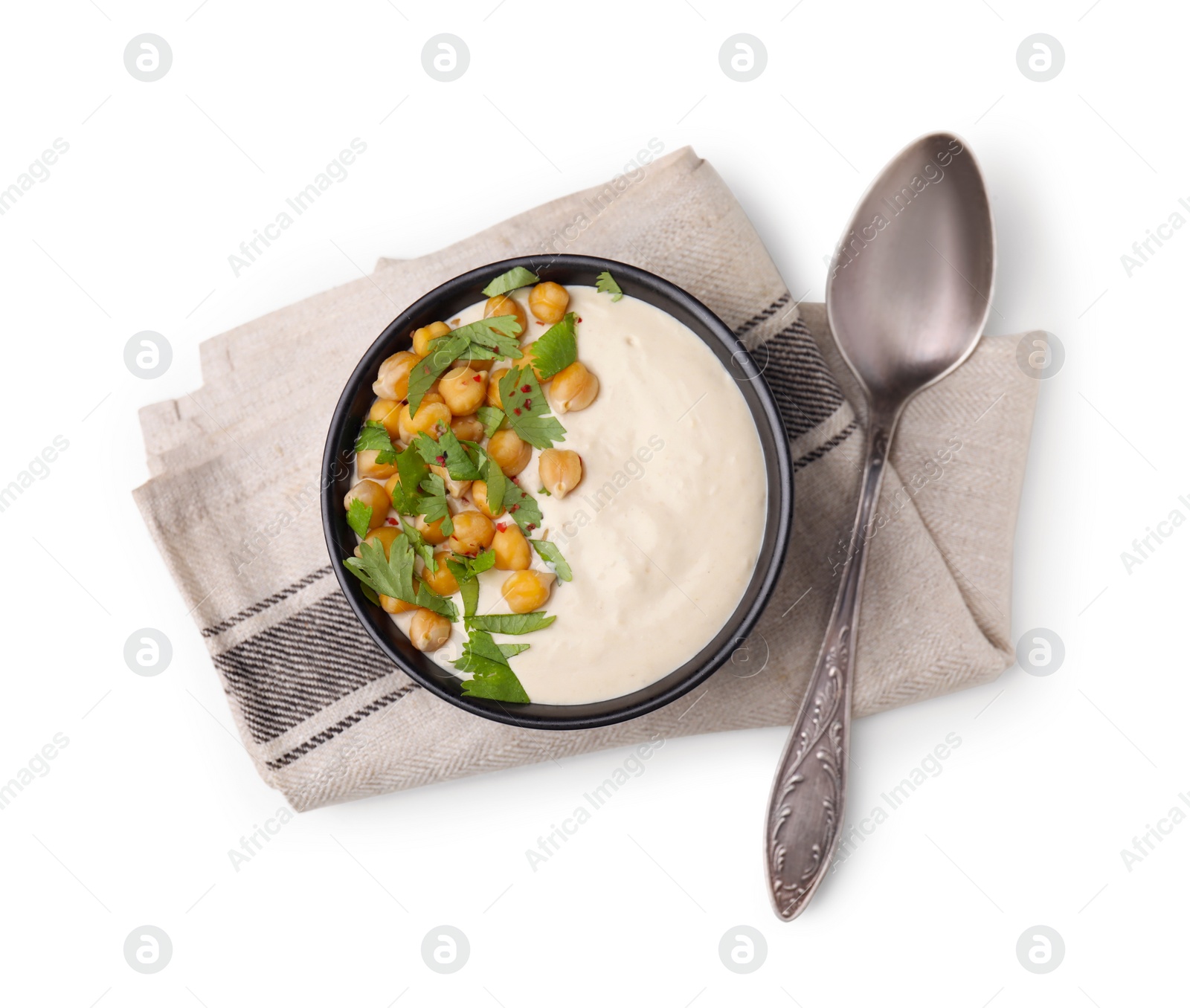 Photo of Tasty chickpea soup in bowl, spoon and napkin on white background, top view