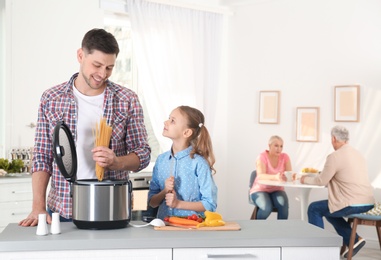 Photo of Father and daughter preparing food with modern multi cooker in kitchen