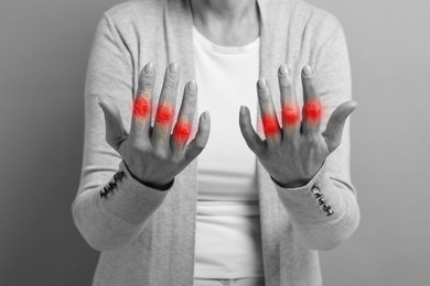 Image of Arthritis symptoms. Woman suffering from pain in her fingers on background, closeup. Black and white effect with red accent in painful area