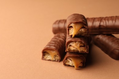 Photo of Sweet tasty chocolate bars with caramel on beige background, closeup. Space for text