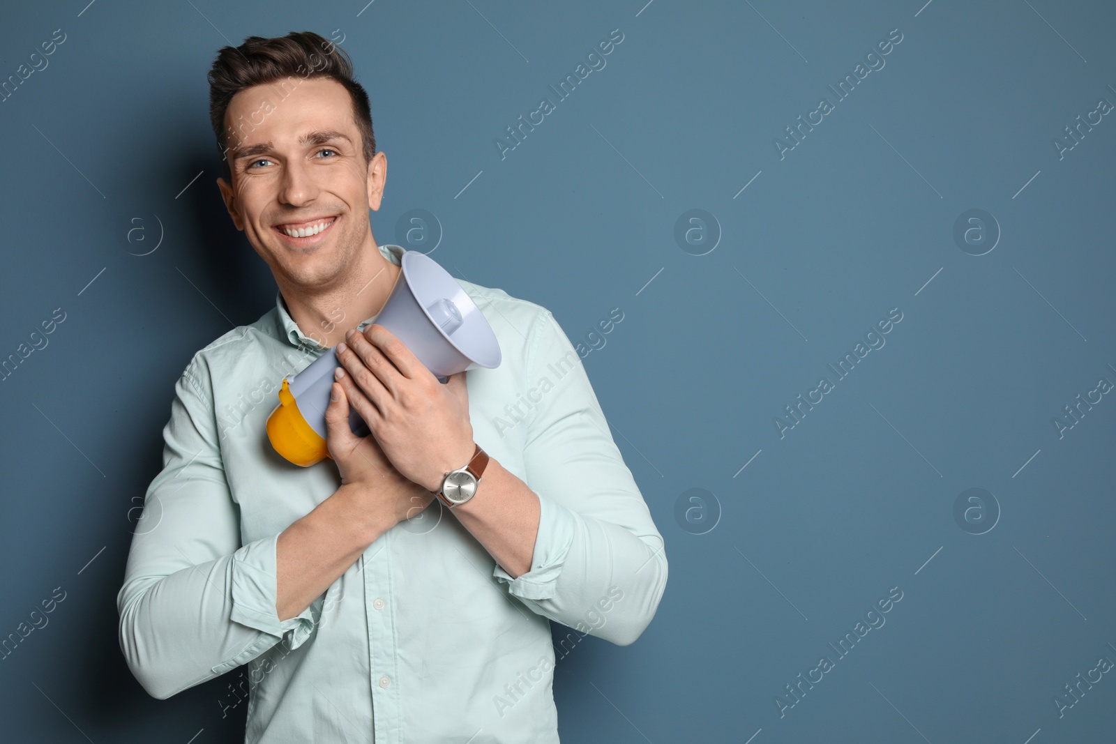 Photo of Young man with megaphone on color background