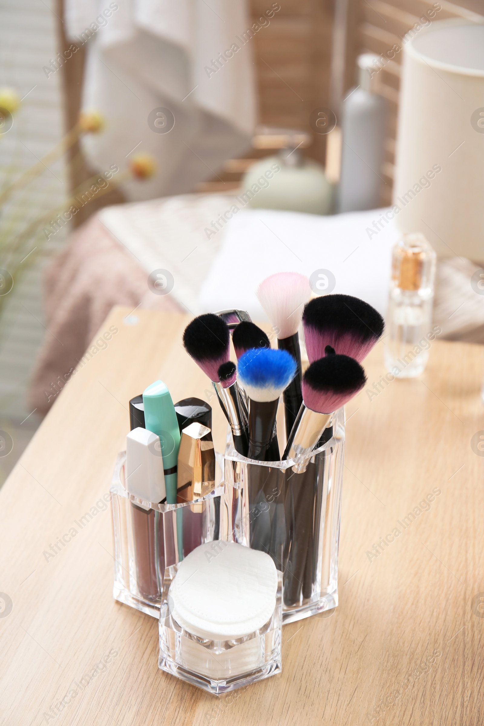 Photo of Organizer with makeup cosmetic products on wooden table in room