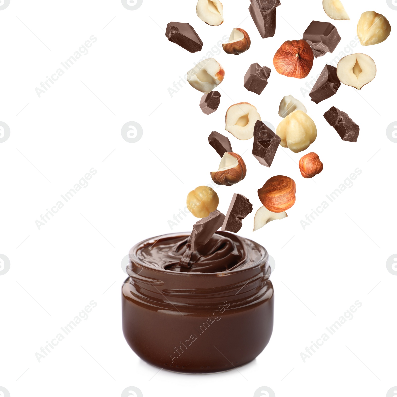 Image of Making yummy chocolate paste. Hazelnuts and pieces of chocolate falling into jar on white background