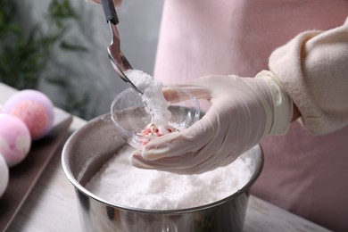 Photo of Woman in gloves making bath bomb at table indoors, closeup