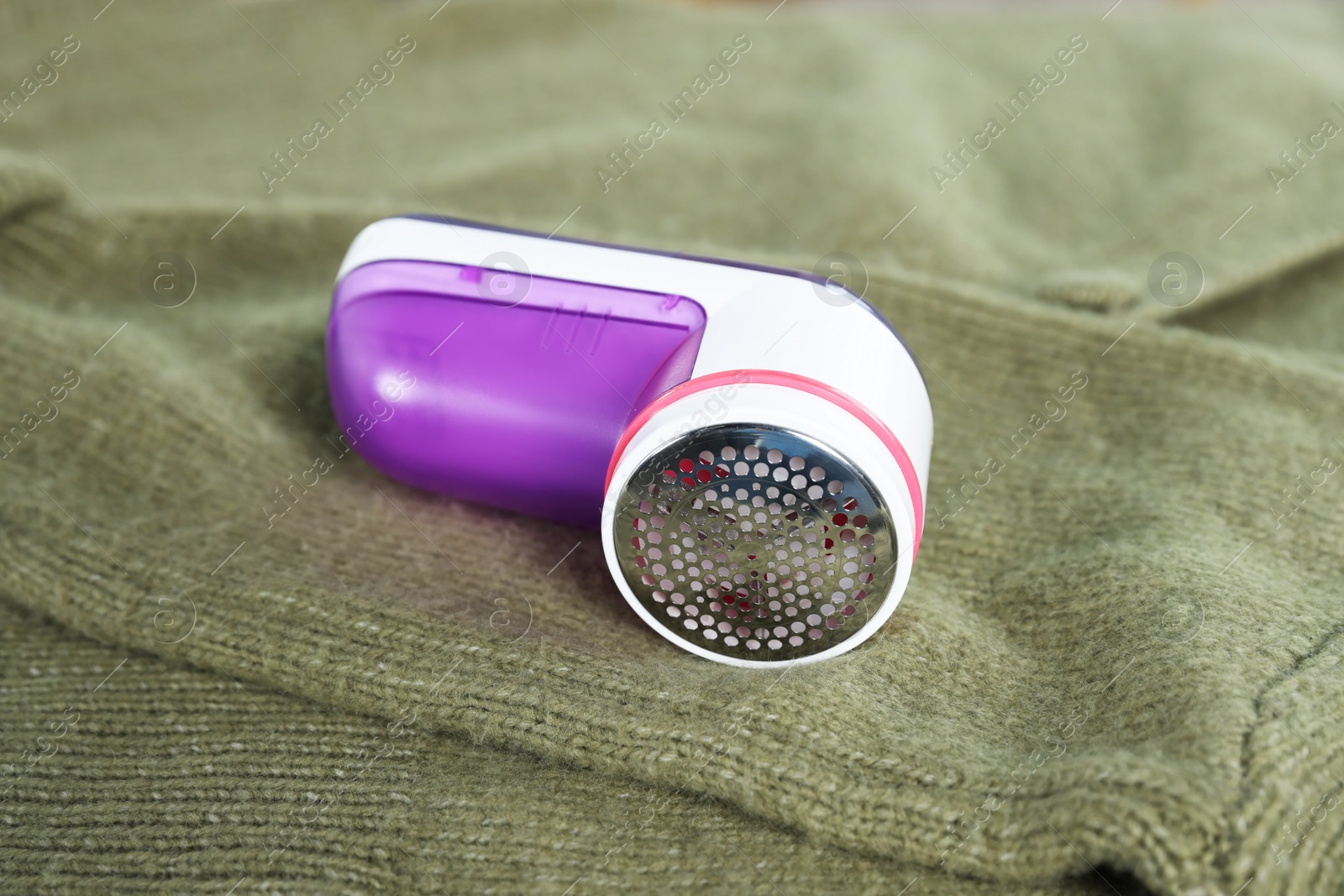 Photo of Modern fabric shaver on olive cloth indoors, closeup