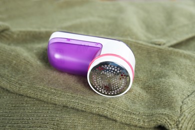 Photo of Modern fabric shaver on olive cloth indoors, closeup