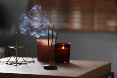 Aromatic incense sticks smoldering on table indoors, space for text