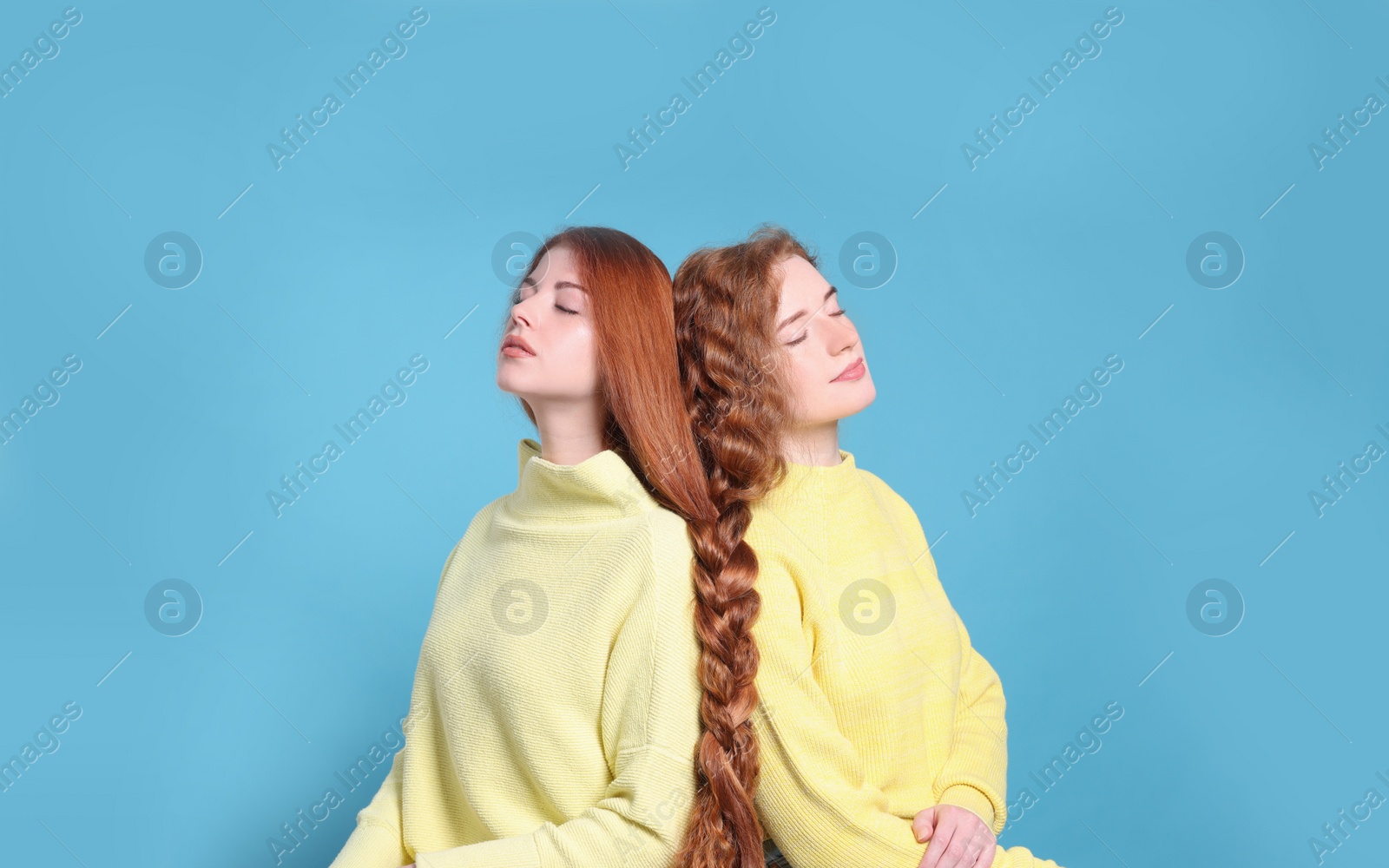 Photo of Portrait of beautiful young redhead sisters on light blue background