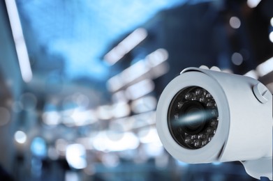 Modern security CCTV camera against blurred background, space for text