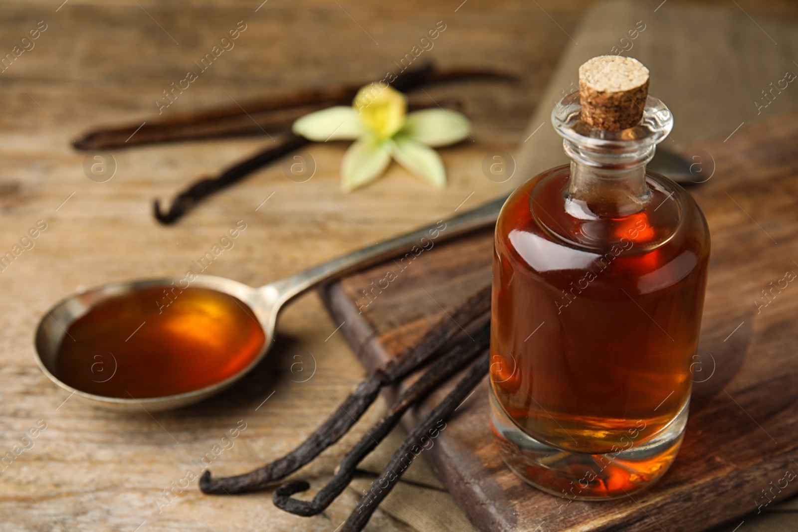 Photo of Aromatic homemade vanilla extract on wooden table, closeup. Space for text