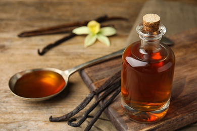 Photo of Aromatic homemade vanilla extract on wooden table, closeup. Space for text