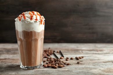 Glass of coffee with caramel topping on wooden table