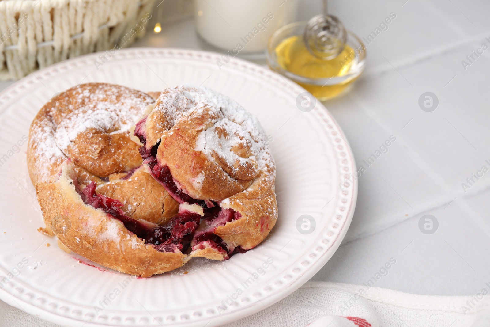 Photo of Delicious buns with sugar powder and berries on white tiled table, space for text