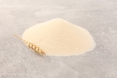 Photo of Pile of uncooked organic semolina and spikelet on grey table