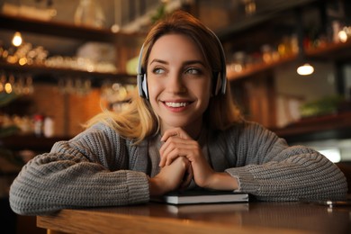 Photo of Woman listening to audiobook at table in cafe