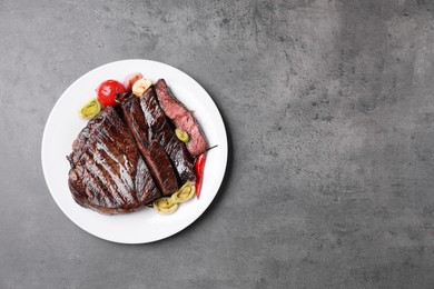 Photo of Delicious grilled beef meat on grey table, top view. Space for text