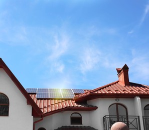 Photo of House with installed solar panels on roof under blue sky. Alternative energy source