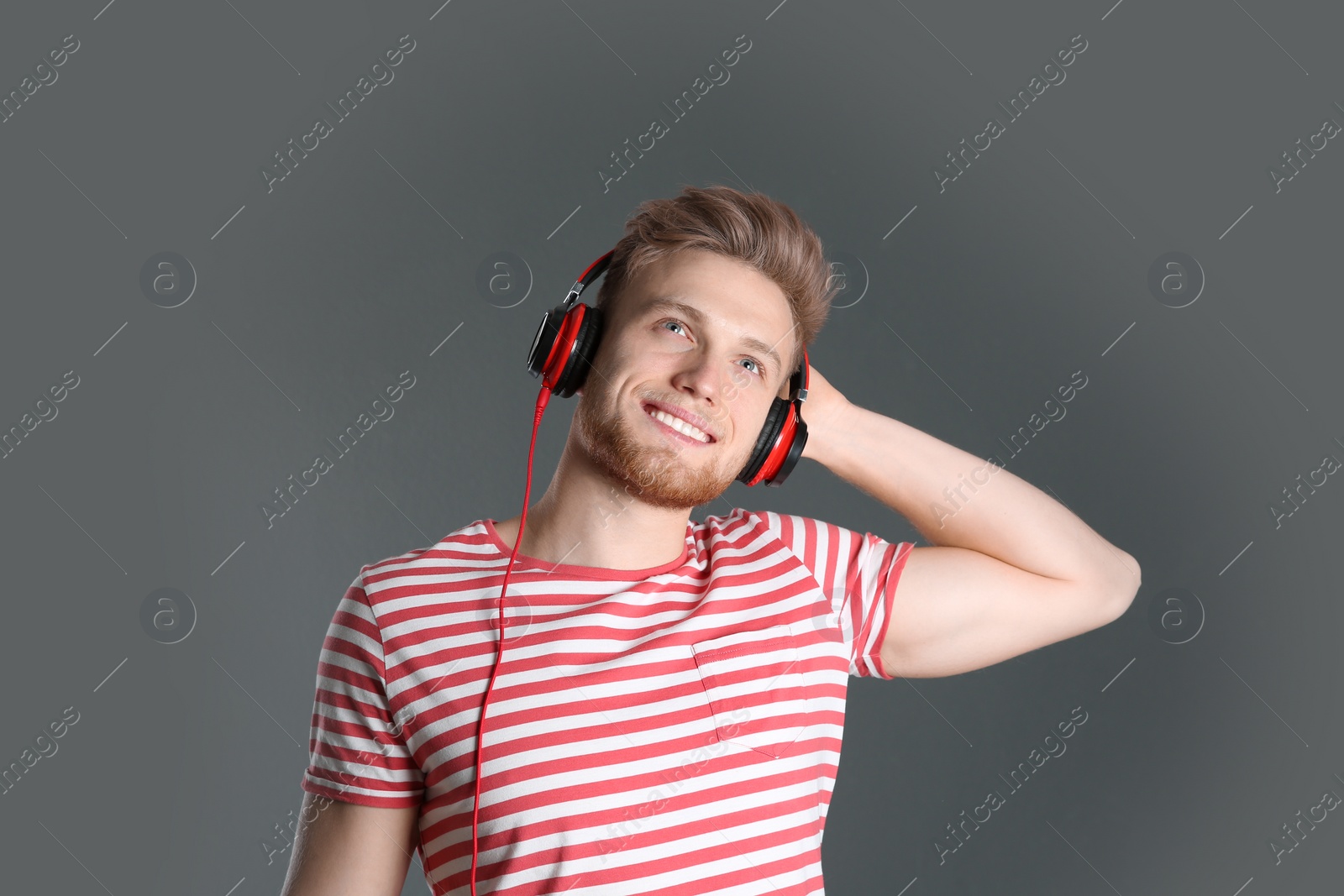 Photo of Handsome young man listening to music with headphones on color background